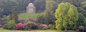 The Temple of Apollo and Rhododendrons reflected in the lake at Stourhead, Wiltshire.