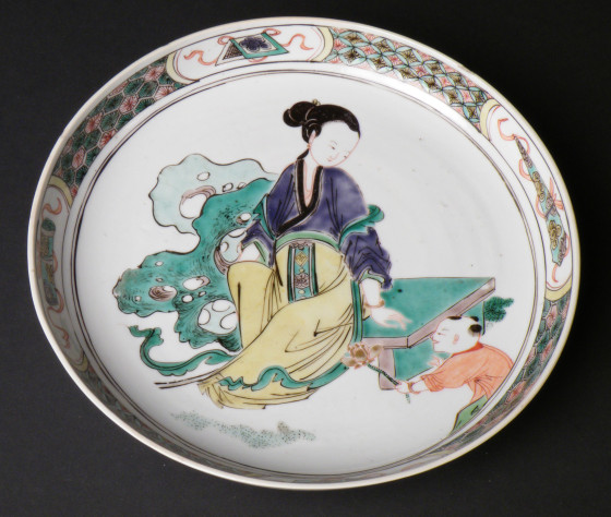 Chinese porcelain saucer dish decorated with a female figure sitting on a bench with a child offering her a lotus flower, Kangxi period (1662-1722), at Polesden Lacey, NT 1245638.1. ©National Trust/Jane Mucklow