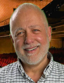 Headshot of John Kenrick. White man, balding with beard. Wearing a plaid print shirt