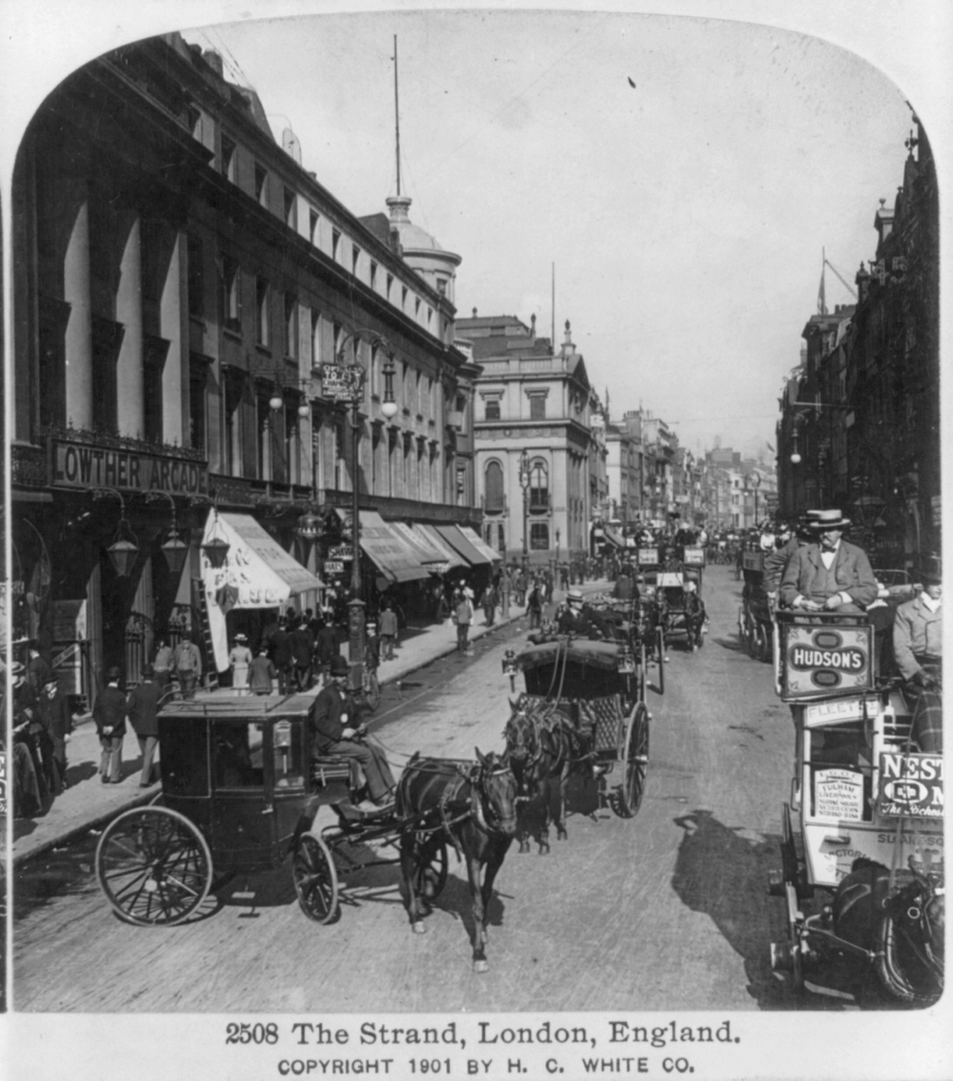 Black and white photograph of The Strand. Buildings and horse drawn carriages in street